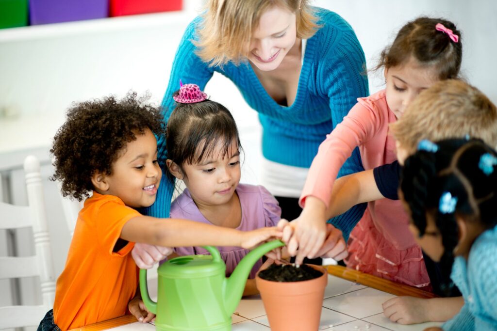Children and an educator working together to plant seeds in a pot during an educational gardening activity.